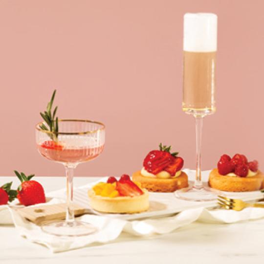 Two glasses of champagne served to sweet strawberry desserts